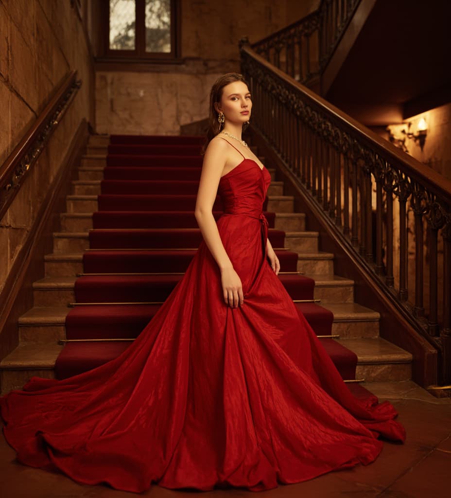  good quality, high quality, a 2 old is descending a grand staircase staircase. she is smiling. pale skin. she is . she is wearing a very big and long extravagant and gorgeous red . she is wearing extravagant jewelry. she is . her s are . enormous, mive s. her entire body is shown including her feet. photo.