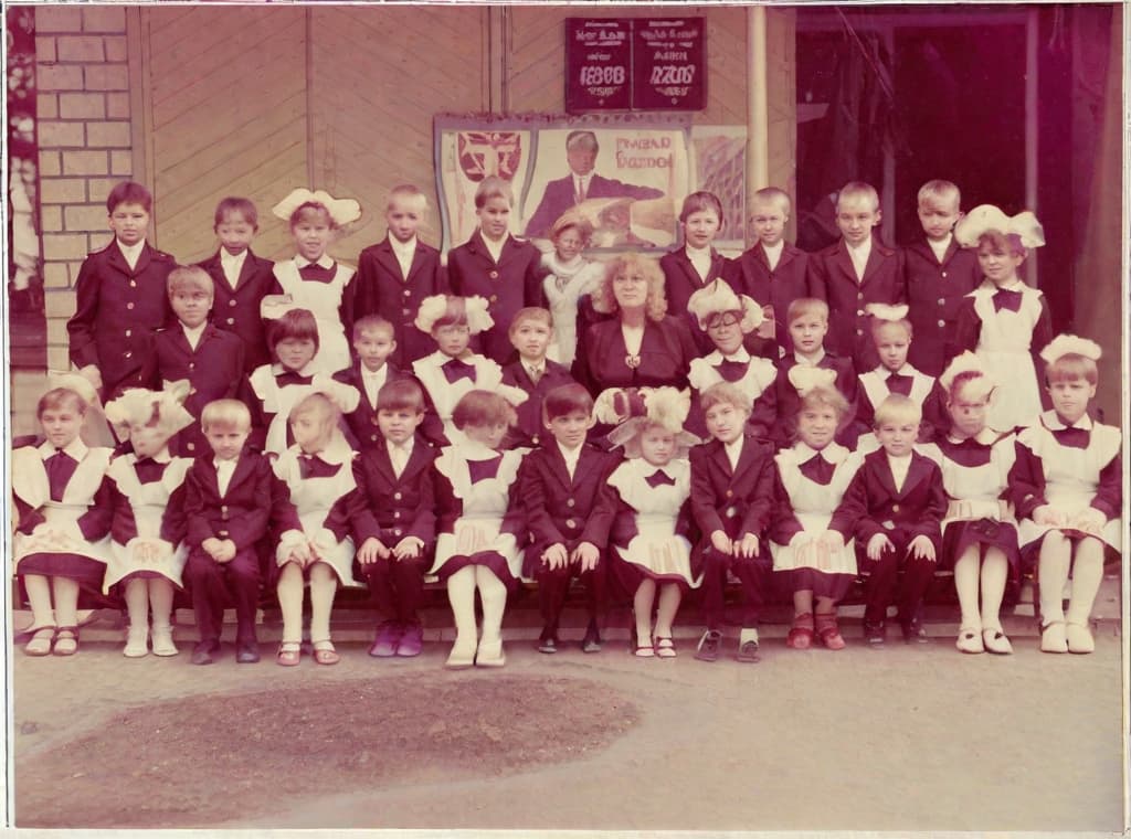  This photo was taken on September 1st 1986, exactly 128 days, or 4 months and 4 days, after the Chernobyl catastrophe took place. It captures my first day at in Gomel, Belarus. I had just turned that summer. In the photo, one can see my clmates and our teacher. Some are standing with their arms hanging beside their bodies, while others are seated on a low bench with their hands neatly placed on their . The students are arranged in three lines: 10 in the 3rd (top) back line, 9 in the 2nd (middle) line, and 13 in the 1st front line, totaling 32 students. There are 17 boys and 15 s, distinguished by the dress code. My friend Genadi is 4th from the right in the 3rd (top) line. I am seated in the very center of the