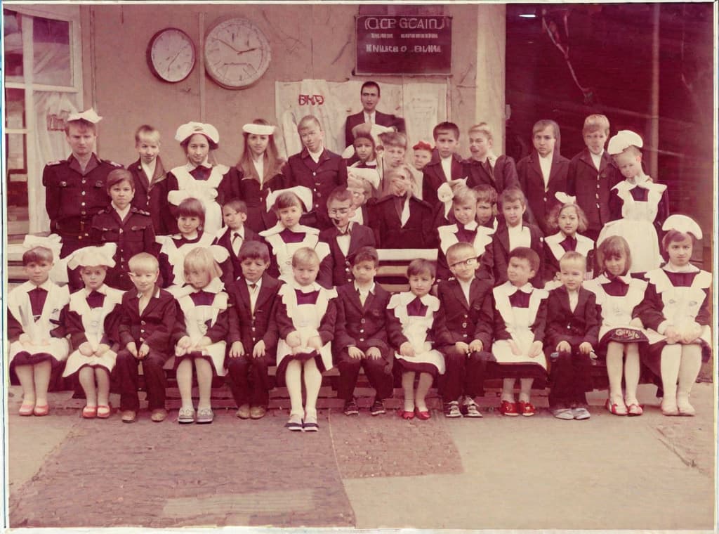  This photo was taken on September 1st 1986, exactly 128 days, or 4 months and 4 days, after the Chernobyl catastrophe took place. It captures my first day at in Gomel, Belarus. I had just turned that summer. In the photo, one can see my clmates and our teacher. Some are standing with their arms hanging beside their bodies, while others are seated on a low bench with their hands neatly placed on their . The students are arranged in three lines: 10 in the 3rd (top) back line, 9 in the 2nd (middle) line, and 13 in the 1st front line, totaling 32 students. There are 17 boys and 15 s, distinguished by the dress code. My friend Genadi is 4th from the right in the 3rd (top) line. I am seated in the very center of the