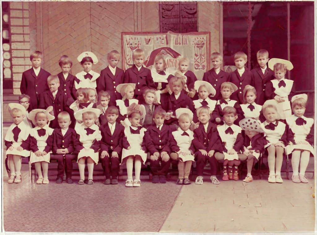  This photo was taken on September 1st 1986, exactly 128 days, or 4 months and 4 days, after the Chernobyl catastrophe took place. It captures my first day at in Gomel, Belarus. I had just turned that summer. In the photo, one can see my clmates and our teacher. Some are standing with their arms hanging beside their bodies, while others are seated on a low bench with their hands neatly placed on their . The students are arranged in three lines: 10 in the 3rd (top) back line, 9 in the 2nd (middle) line, and 13 in the 1st front line, totaling 32 students. There are 17 boys and 15 s, distinguished by the dress code. My friend Genadi is 4th from the right in the 3rd (top) line. I am seated in the very center of the