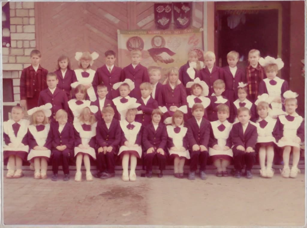  This photo was taken on September 1st 1986, exactly 128 days, or 4 months and 4 days, after the Chernobyl catastrophe took place. It captures my first day at in Gomel, Belarus. I had just turned that summer. In the photo, one can see my clmates and our teacher. Some are standing with their arms hanging beside their bodies, while others are seated on a low bench with their hands neatly placed on their . The students are arranged in three lines: 10 in the 3rd (top) back line, 9 in the 2nd (middle) line, and 13 in the 1st front line, totaling 32 students. There are 17 boys and 15 s, distinguished by the dress code. My friend Genadi is 4th from the right in the 3rd (top) line. I am seated in the very center of the