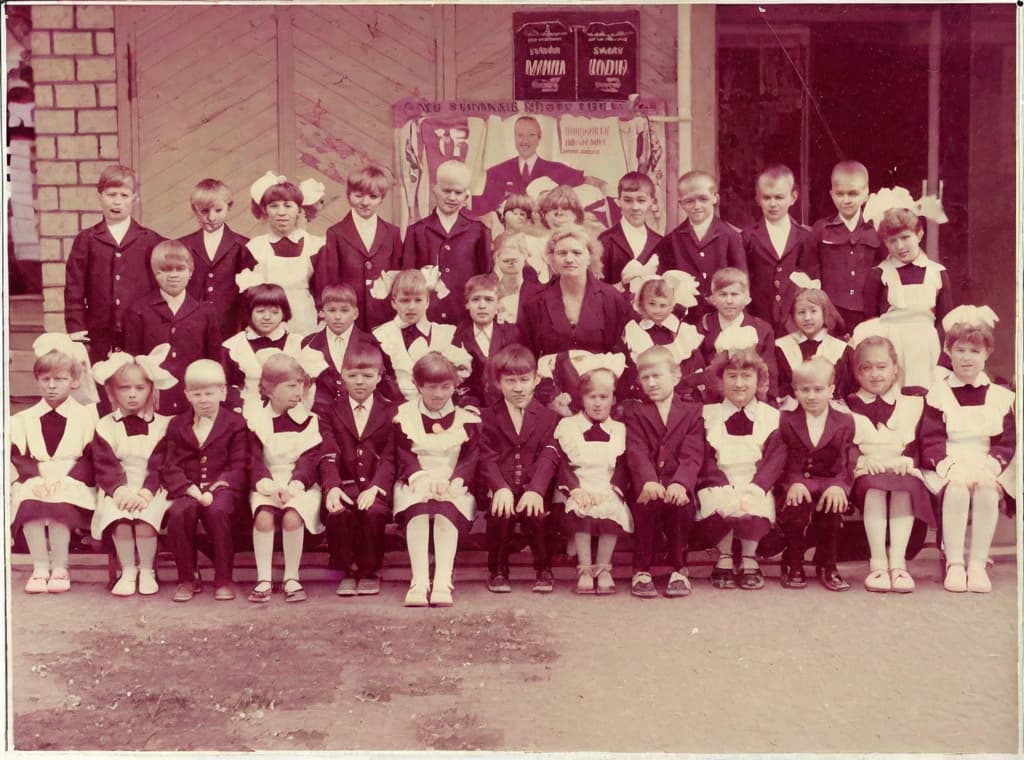  This photo was taken on September 1st 1986, exactly 128 days, or 4 months and 4 days, after the Chernobyl catastrophe took place. It captures my first day at in Gomel, Belarus. I had just turned that summer. In the photo, one can see my clmates and our teacher. Some are standing with their arms hanging beside their bodies, while others are seated on a low bench with their hands neatly placed on their . The students are arranged in three lines: 10 in the 3rd (top) back line, 9 in the 2nd (middle) line, and 13 in the 1st front line, totaling 32 students. There are 17 boys and 15 s, distinguished by the dress code. My friend Genadi is 4th from the right in the 3rd (top) line. I am seated in the very center of the