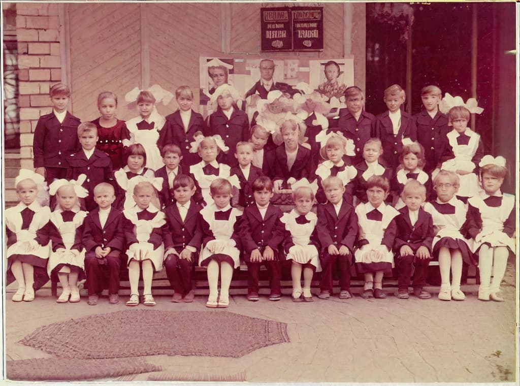  This photo was taken on September 1st 1986, exactly 128 days, or 4 months and 4 days, after the Chernobyl catastrophe took place. It captures my first day at in Gomel, Belarus. I had just turned that summer. In the photo, one can see my clmates and our teacher. Some are standing with their arms hanging beside their bodies, while others are seated on a low bench with their hands neatly placed on their . The students are arranged in three lines: 10 in the 3rd (top) back line, 9 in the 2nd (middle) line, and 13 in the 1st front line, totaling 32 students. There are 17 boys and 15 s, distinguished by the dress code. My friend Genadi is 4th from the right in the 3rd (top) line. I am seated in the very center of the