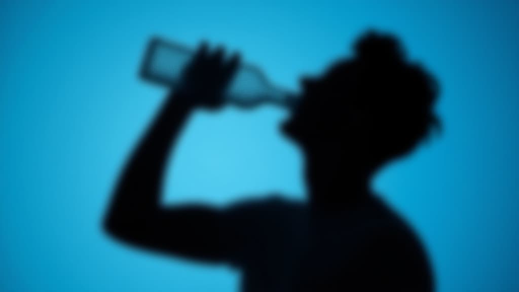  silhouette of man drinking water from a bottle on a blue background, closeup