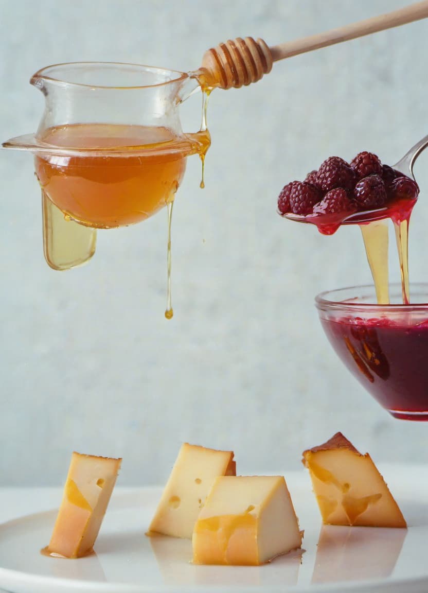  the cheese is poured with honey, next to raspberry jam and a few berries, a delicious cover, a beautiful reflection, film photography style