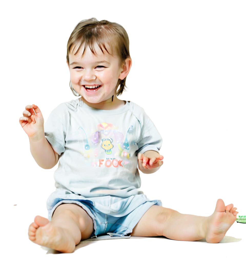  a little child sitting on the floor playing and smiling, film photography style